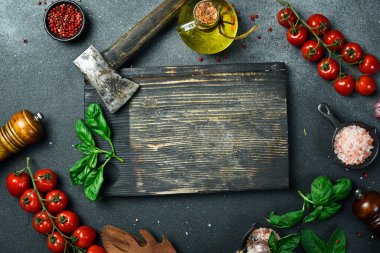 Kesme tahtası, sebze ve mutfak gereçleri siyah bir masada. Metin için boş alan. Üst görünüm.