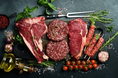 Et ve et ürünleri seti. Biftek, pirzola, kebap ve hamburger köftesi. Siyah taştan bir arka planda. Üst görünüm.