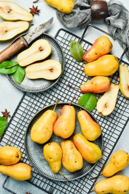 Armut. Tatlı armutlar tabakta ve armut dilimleri üstte. Gri masa. Sonbahar meyveleri.