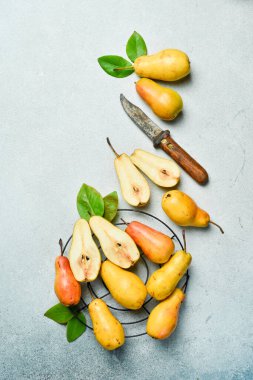 Gri masada yaprakları olan taze armutlar. Sonbahar meyveleri. Üst İnceleme.