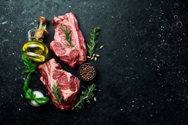 İki çiğ mermer et bifteği ve koyu ahşap arka planda baharatlar. - Et. Üst Manzara. Metin için boş alan.