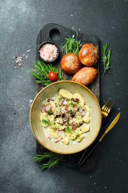 Pastırmalı ve ekşi kremalı patates gnocchi. Siyah taştan bir arka planda. Ekmek.