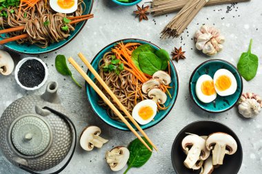 Yumurtalı, mantarlı ve mikroyeşillikli Japon sobası. Gri taştan bir arka planda. Üst görünüm.