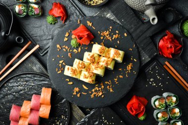 Kaba bir arka planda balık ve peynirli Japon suşisi. Suşi, nigiri, maki, zencefil turşusu, wasabi, soya sosu. Suşi masada hazır..