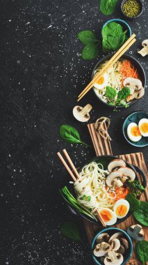 Geleneksel Japon udon erişteleri. Bir kase yumurtalı, mantarlı, yeşil soğanlı erişte. Siyah bir arka planda. Üst görünüm.