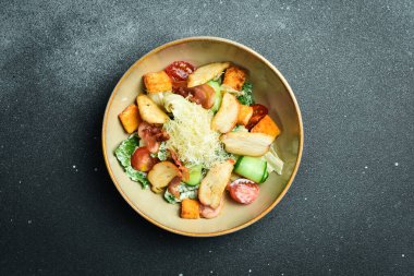 Tavuk ve sebzeli Sezar salatası. Tabakta. Restoran servisi. Kapatın. Karanlık bir taş arka planda.