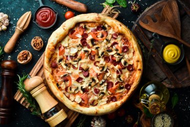 Bavyera sosisi, mantar ve peynirli pizza. Siyah taşlı arka planda klasik pizza. Üst görünüm.