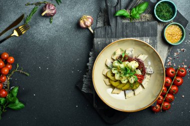 Patates ve turşulu tuzlu ringa balığı. Tabakta. Restoran servisi. Kapatın. Karanlık bir taş arka planda.