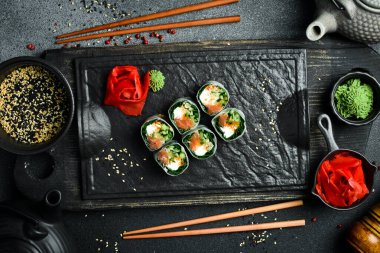 Somon, lahana yaprağı ve krem peynirli suşi ruloları. Wasabi sosu ve zencefil turşusuyla servis edilir. Geleneksel Japon yemekleri. Kapat..