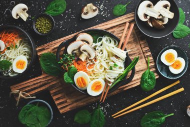 Yumurtalı, mantarlı, yeşil soğanlı Buda Kasesi Eriştesi. Siyah bir arka planda. Üst görünüm.