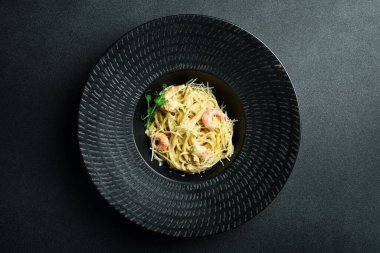 Siyah kasede karides ve peynirli makarna. Karanlık bir arkaplanda, yakın plan.