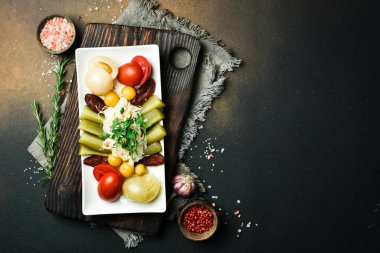 Salatalık, domates, lahana turşulu bir tabak. Aperatif. Karanlık bir taş arka planda. Metin için boş alan.