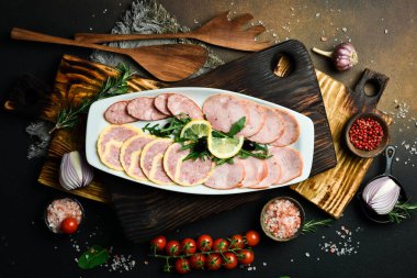 Tabakta farklı türde salam kesmek. Koyu bir arkaplanda.