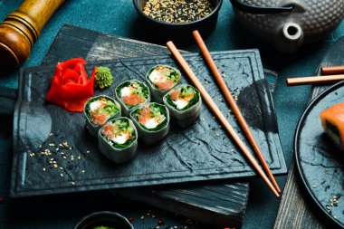 Somon, lahana yaprağı ve krem peynirli suşi ruloları. Wasabi sosu ve zencefil turşusuyla servis edilir. Geleneksel Japon yemekleri. Kapat..