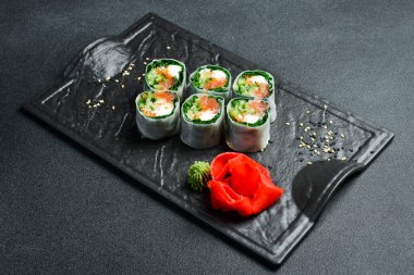 Somon, lahana yaprağı ve krem peynirli suşi ruloları. Wasabi sosu ve zencefil turşusuyla servis edilir. Geleneksel Japon yemekleri. Kapat..