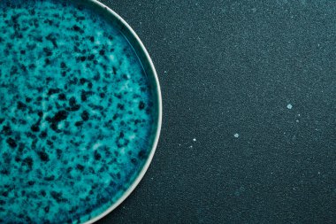 Boş seramik tabak, hassas yatak akhuamarin turkuaz rengi. Siyah arka plan. Tepesi patlıyor. Uyu artık..