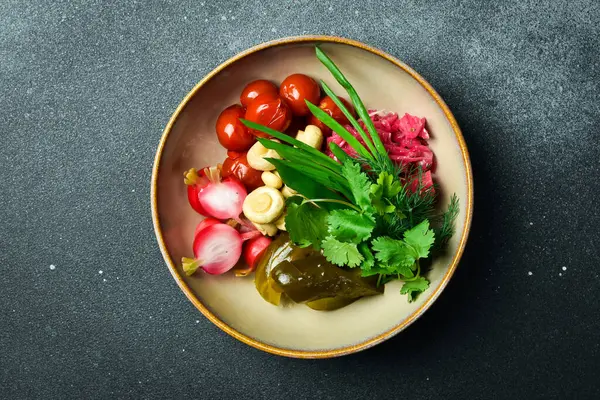 Sebze turşusu: lahana, salatalık, domates. Kapatın. Bir tabakta Siyah bir taşın arkasında.