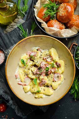 Pastırmalı ve ekşi kremalı patates gnocchi. Siyah taştan bir arka planda. Ekmek.