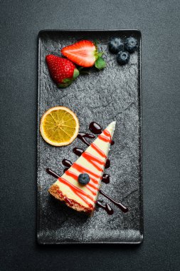 Çilek soslu ve yabanmersinli cheesecake. Tatlı. Karanlık bir arkaplanda, yakın plan.