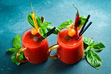 Buzlu Bloody Mary kokteyli. Baharatlı ve fesleğenli bir bardak domates alkollü kokteyl. Koyu taştan bir masada..