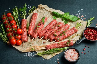 Çiğ Lyulya kebabı, baharat ve otlarla birlikte, pişirmeye hazır. Karanlık bir taş arka planda. Üst görünüm....