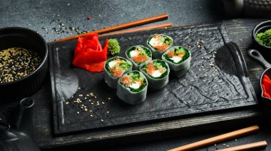 Somon, lahana yaprağı ve krem peynirli suşi ruloları. Wasabi sosu ve zencefil turşusuyla servis edilir. Geleneksel Japon yemekleri. Kapat..