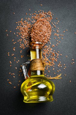 Keten tohumu yağı ve keten tohumu, yakın plan. Karanlık bir arka planda. Üst görünüm.