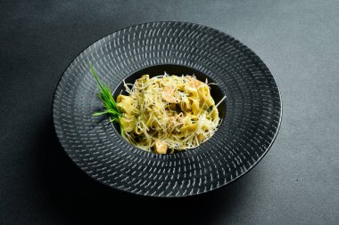 Pesto soslu makarna ve siyah kasede tavuk. Karanlık bir arkaplanda, yakın plan.
