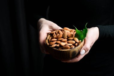 Kadın ellerinde bir kase badem. Sağlıklı yüksek kalorili vejetaryen gıda konsepti. Kapat..