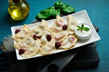 Beyaz kare tabakta vişneli ve ekşi kremalı hamur tatlısı. Metin için boş alan. Karanlık bir arka planda.