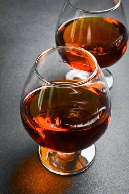 Eskimiş bir konyak ya da karanlık bir masada konyak. Güçlü alkollü içecekler. Beton bir arka planda.