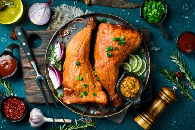 Siyah tabakta limon, biberiye ve baharatla tütsülenmiş tavuk bacağı. Karanlık bir arka planda.