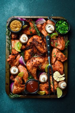 Metal tepside pişirilmiş tavuk ve tavuk kanatları. Kırsal tarzda. Karanlık bir arka planda.