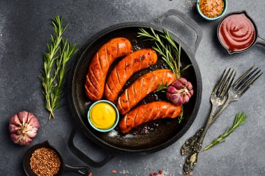 Metal bir tavada ev yapımı sosis. Gri beton arka planda.