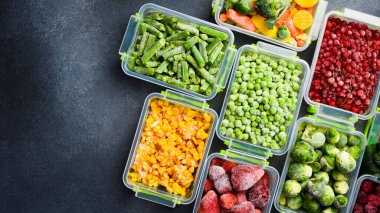 Plastik kaplar ve donmuş sebzeler. Üst Manzara. Gri taştan bir arka planda. Kış erzakları.