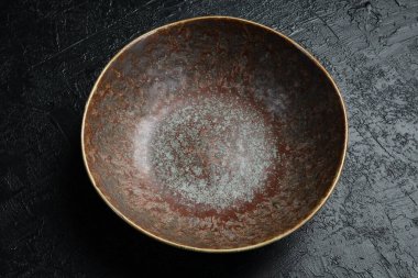 Siyah taş bir masanın üzerinde klasik seramik koyu kâse. Yakın plan..