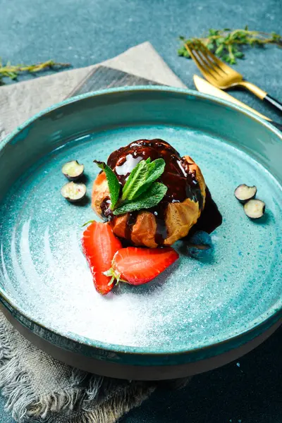 Çikolatalı ve çilekli kremalı pasta. Karanlık bir taş arka planda.