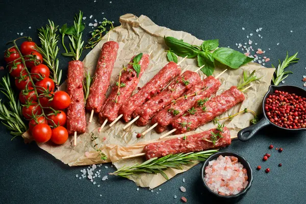 Çiğ Lyulya kebabı, baharat ve otlarla birlikte, pişirmeye hazır. Karanlık bir taş arka planda. Üst görünüm....
