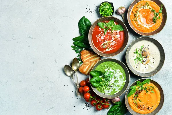 Renkli sebze çorbaları: ıspanak, mantar, havuç ve balkabağı. Bir kasede. Beslenme konsepti. Üst görünüm.