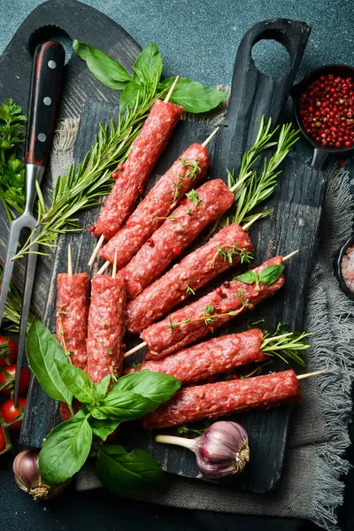 Çiğ Lyulya kebabı, baharat ve otlarla birlikte, pişirmeye hazır. Karanlık bir taş arka planda. Üst görünüm....