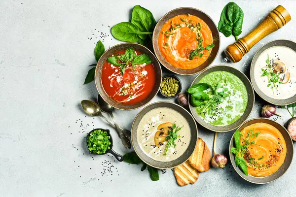 Renkli sebze çorbaları: ıspanak, mantar, havuç ve balkabağı. Bir kasede. Beslenme konsepti. Üst görünüm.