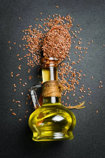 Keten tohumu yağı ve keten tohumu, yakın plan. Karanlık bir arka planda. Üst görünüm.