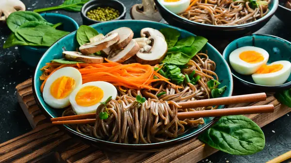 Yumurtalı, mantarlı ve mikroyeşillikli karabuğday sobalı makarna. Gri taştan bir arka planda. Yan görüş. Sağlıklı yemek..