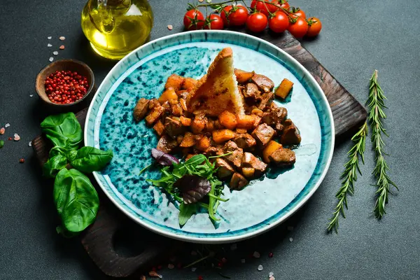 Geleneksel Azerbaycan yemekleri. Sebze ve baharatla pişirilmiş kuzu ciğeri. Metin için boş alan. Karanlık bir arka planda.