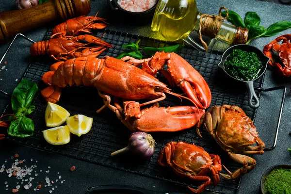 Kaynamış ıstakoz, yengeç ve kerevit. Siyah tahtada limon ve fesleğen. Yan görünüm.