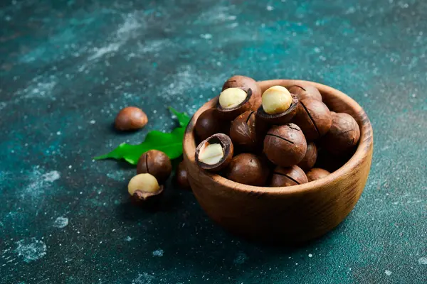 Arka planda ahşap kasede Macadamia fındıkları. Uzayı kopyala Süper yiyecek, vegan, vejetaryen gıda konsepti. Sağlıklı atıştırmalık..