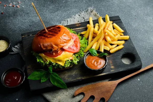 Geleneksel hamburger ve ketçaplı patates kızartması. Fast food. Karanlık bir arkaplanda, yakın plan.
