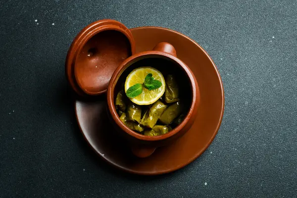 Lezzetli dolma (sarma) dolma yaprağı pilavı. Kil sürahisinde. Kapatın. Karanlık bir arka planda.