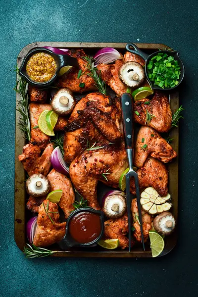 Metal tepside pişirilmiş tavuk ve tavuk kanatları. Kırsal tarzda. Karanlık bir arka planda.