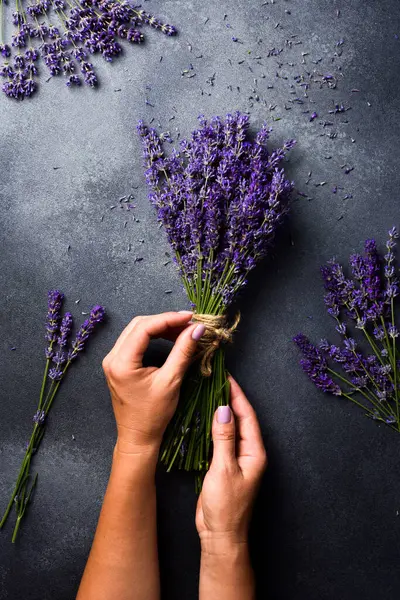 Bir demet lavanta. Kadınların elleri lavanta çiçeği bağlamaya hazırlanıyor. Üst görünüm.